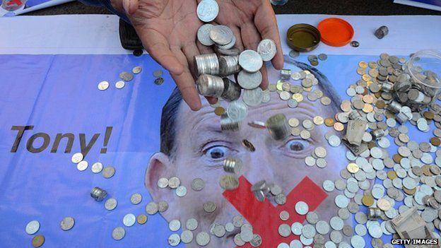 An Indonesian man pours coins from his hands as a 'donation' to Australia's Prime Minister Tony Abbott in Jakarta on 22 February.