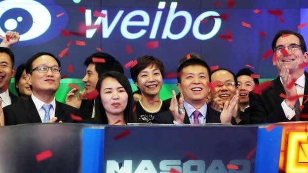 China's Weibo CEO Charles Chao (center) stands with Robert Greifeld, Nasdaq CEO, moments after Weibo began trading on the Nasdaq exchange under the ticker symbol WB on April 17, 2014 in New York City.