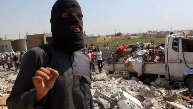 An image grab taken from an AFPTV video on September 16, 2014 shows a jihadist from the Islamic State (IS) group standing on the rubble of houses after a Syrian warplane was reportedly shot down by IS militants over the Syrian town of Raqa