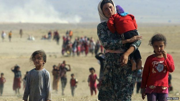 Displaced people from the minority Yazidi sect, fleeing violence from forces loyal to the Islamic State in Sinjar town, walk towards the Syrian border on the outskirts of Sinjar mountain near the Syrian border town of Elierbeh of Al-Hasakah Governorate in this August 11, 2014 file photo