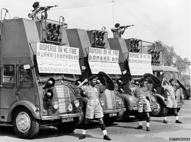 Members of the Singapore Police Riot Squad during race riots between Chinese and Malay groups in 1964. Their vehicles display warning signs reading 'Disperse Or We Fire'.