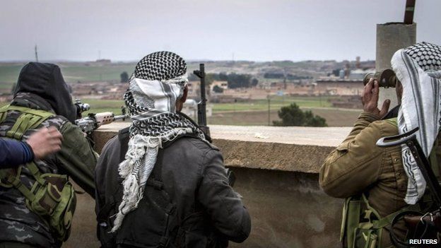 Fighters of the Kurdish People's Protection Units (YPG) carry their weapons and use a pair of binoculars in the outskirts of Tal Tamr town as they monitor the movements of Islamic State fighters