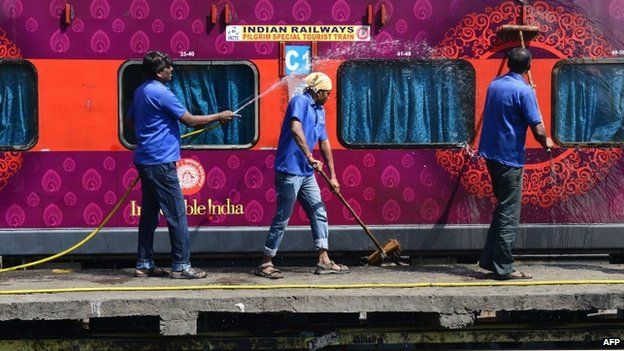 Indian railway workers clean train coaches at a railway station in Secunderabad on February 26, 2015