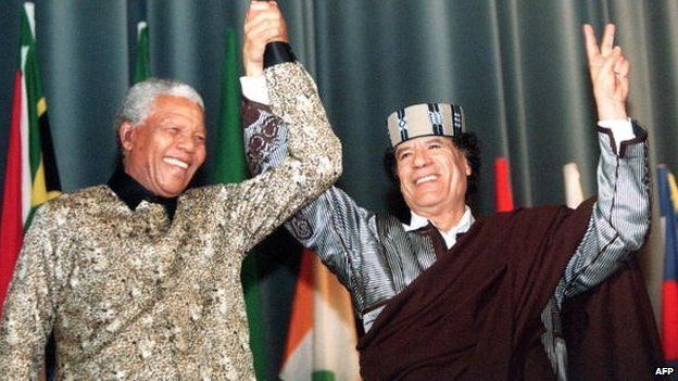 Libyan Leader Muammar Gaddafi flashes the 'V' sign as he stands with South African President Nelson Mandela on 19 March 1999 at the end of their speeches at the Libyan parliament in Tripoli