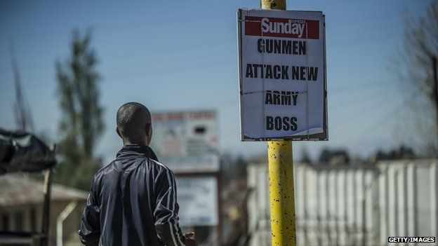 A man stands next to a newspaper advertising in Maseru, Lesotho