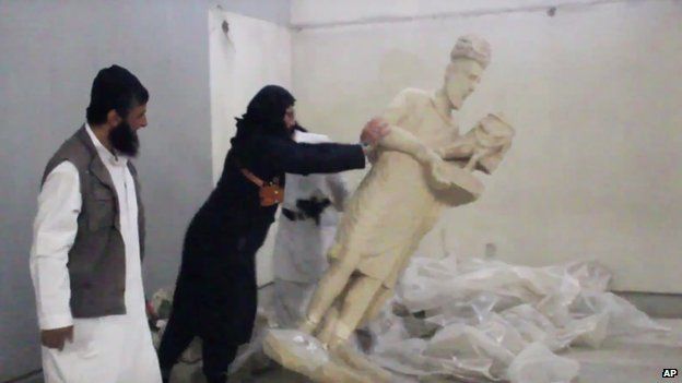 An IS militant appears to push over a statue in Mosul Museum
