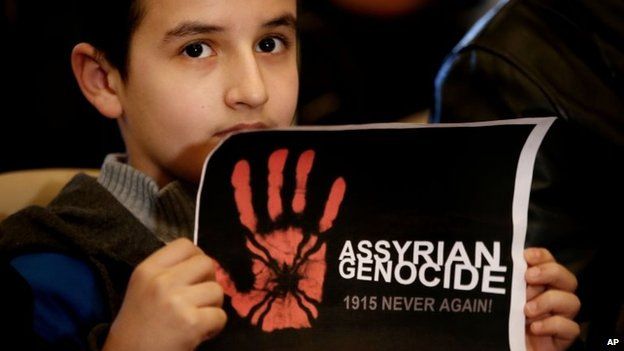 A boy holds up a poster saying "Assyrian genocide: 1915 never again" at a church in Beirut