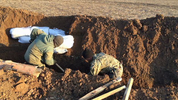 Two men dig trenches in Mariupol