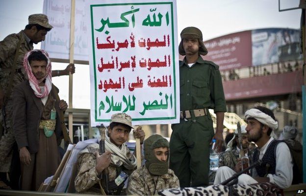 Armed Houthi rebels in Sanaa carry a poster saying: "God is great. Death to America. Death to Israel. A curse on the Jews. Victory to Islam." (23 January 2015)