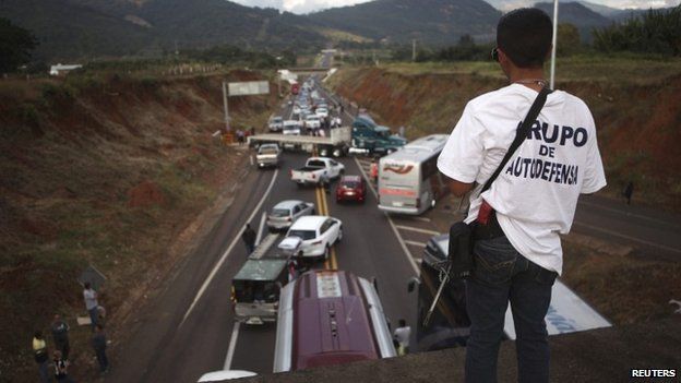A vigilante stands guard on a bridge during a blockade on a highway near the town of Uruapan in Michoacan state