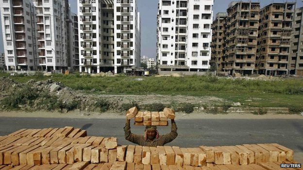 Рабочий складывает на голову кирпичи на строительной площадке жилого комплекса в Калькутте 28 февраля 2015 года.