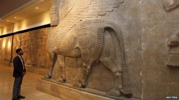 A man looks at ancient Assyrian human-headed winged bull statues at the Iraqi National Museum in Baghdad