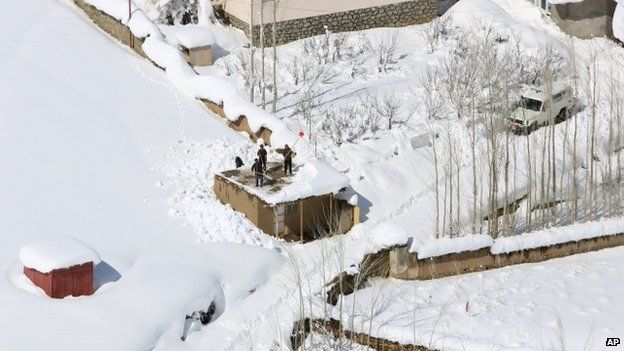 Afghans clean snow from their roofs after the avalanche in the Paryan district of Panjshir province (27 February 2015)