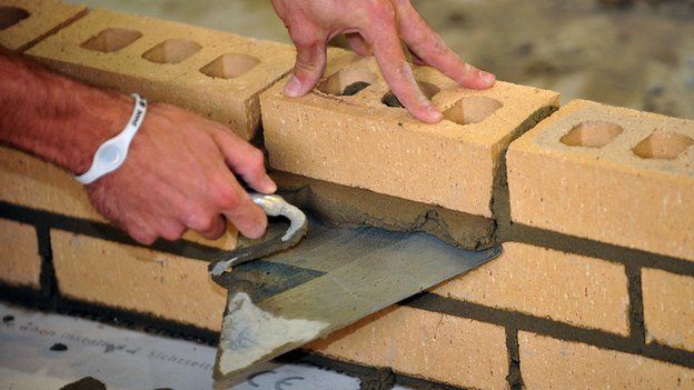 Apprentice bricklayer laying bricks