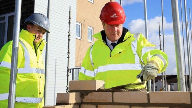 David Cameron lays bricks with apprentice brick layer Josh Adams during a visit to a new housing development in Grays, Essex