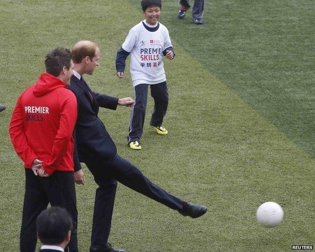 Prince William kicks a ball during a visit to Nanyang Secondary School in Shanghai