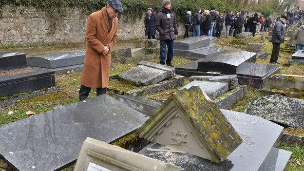 Members of the Jewish community look at broken tombstones after a ceremony at the Jewish cemetery in Sarre-Union