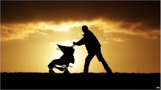 A man pushing a buggy, seen in silhouette at sunset