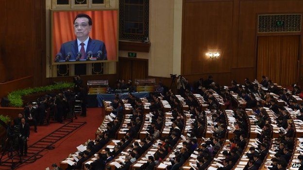 Delegates listen to Chinese premier Li Keqiang (on the screen) as he delivers his work report during the opening of the third session of the 12th National People's Congress at the Great Hall of the People in Beijing on March 5, 2015
