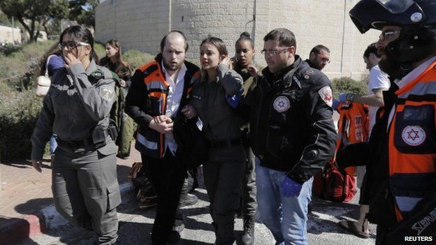 An injured Israeli policewoman clutches her neck in Jerusalem