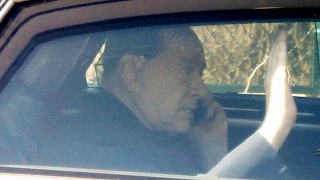 Italy"s former Premier Silvio Berlusconi speaks on a mobile phone as he leaves the "Sacra Famiglia" institute in Cesano Boscone, near Milan