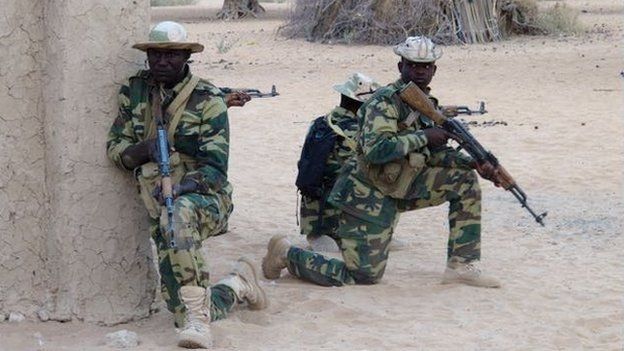 Two Chadian soldiers carrying arms in a desert location