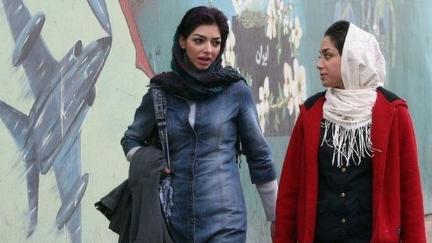 File photo: Two women walk past a mural in the Iranian capital Tehran