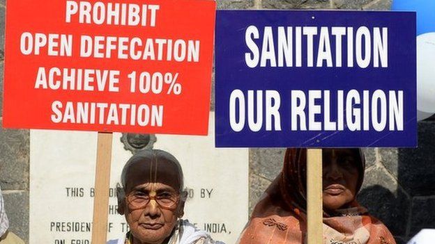 Women holding signs calling for an end to open defecation