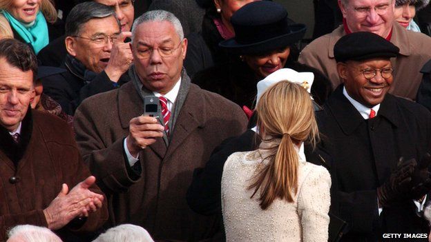 Outgoing Secretary of State Colin Powell takes a picture with his phone of President George W Bush as he leaves the platform at the end of the swearing-in ceremony 20 January 2005