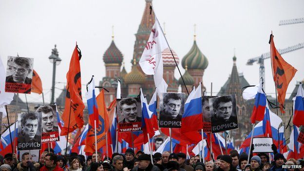 People hold flags and posters during a march to commemorate Kremlin critic Boris Nemtsov near St Basil"s Cathedral in central Moscow