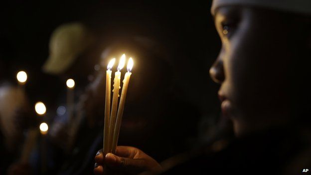 A 13-year-old girl holds three candles at the vigil