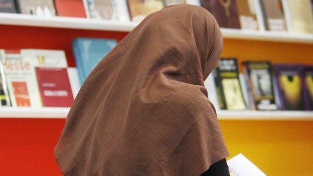 A veiled woman reads a book in front of shelves at the stand of Macedonia at the Leipzig Book Fair, 18 March 2010