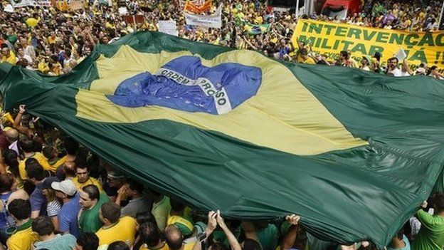 Protesters hold a Brazilian flag aloft