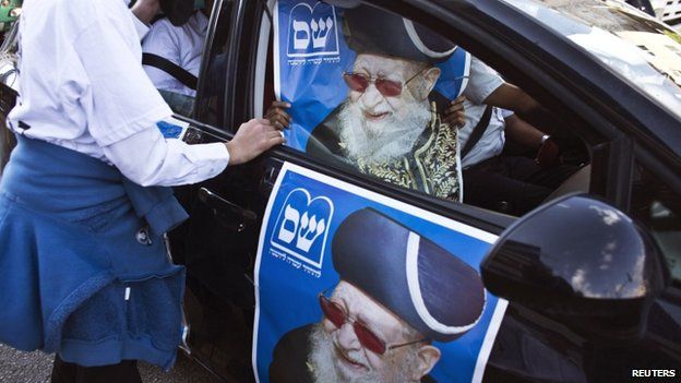 A supporter of the ultra-Orthodox Shas party, or Sephardic Torah Guardians, holds a campaign poster depicting the party"s spiritual leader Rabbi Ovadia Yosef, in Bnei Brak near Tel Aviv March 16, 2015