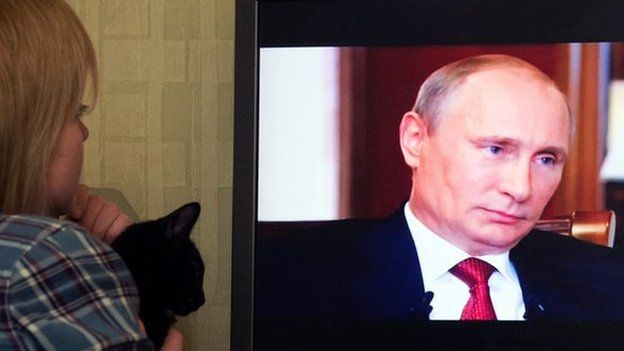 Woman watches Russian President Vladimir Putin (15 March)