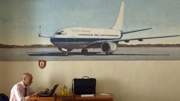 A man works in front of a mural of an aircraft of St Helena Airlines