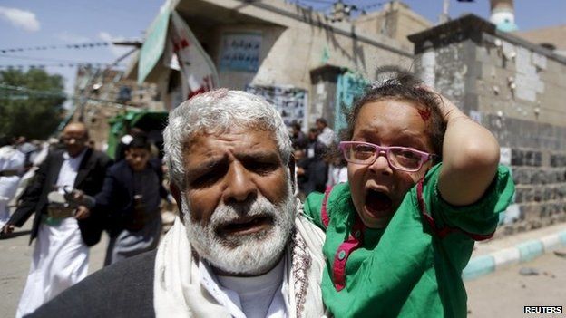 A man carries a wounded girl after a suicide bomb attack on a mosque in Sanaa, Yemen (20 March 2015)