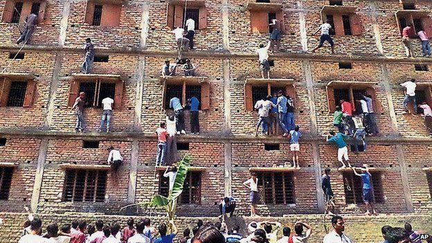 Indians climb the wall of a building to help students appearing in an examination in Hajipur, in the eastern Indian state of Bihar