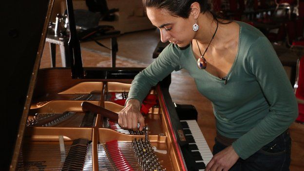 A woman tuning a piano