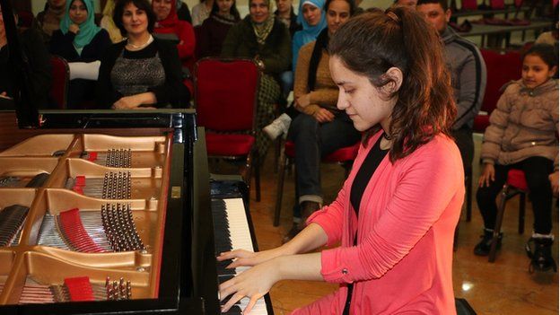 A girl playing a grand piano at a concert