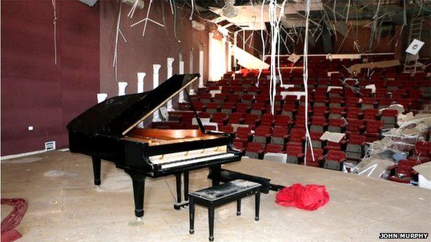 A grand piano in a bombed out concert hall