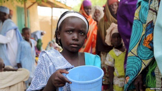 A girl drinks water as women queue for blankets and food given out by Nigerien soldiers in Damasak on 24 March 2015