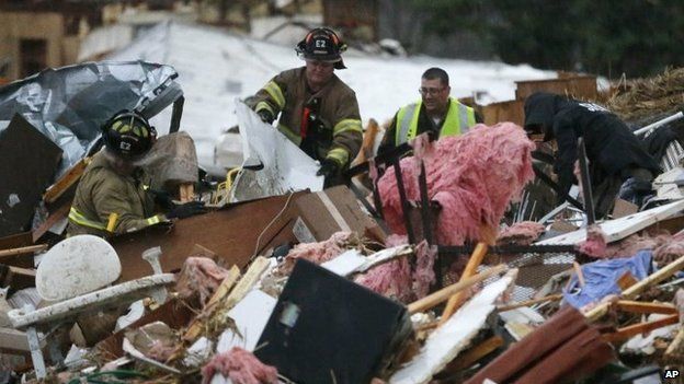 Rescuers work to free a man from a pile of rubble after a round of severe weather hit a mobile home park