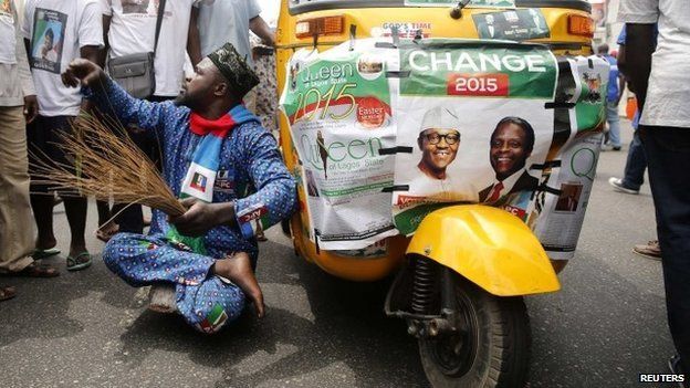 A disabled man gestures next to a vehicle with posters campaigning for All Progressives Congress (APC) Presidential and vice Presidential candidates Muhammadu Buhari and Yemi Osinbajo during a street procession tagged "March for Change" in Lagos on 7 March 2015