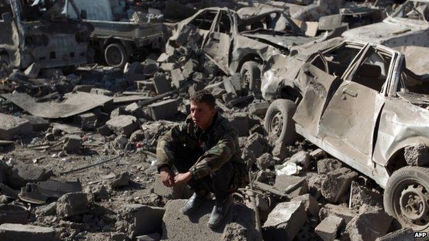 A member of the Yemeni security forces sits near cars destroyed by Saudi-led coalition air strikes in Sanaa (26 March 2015)