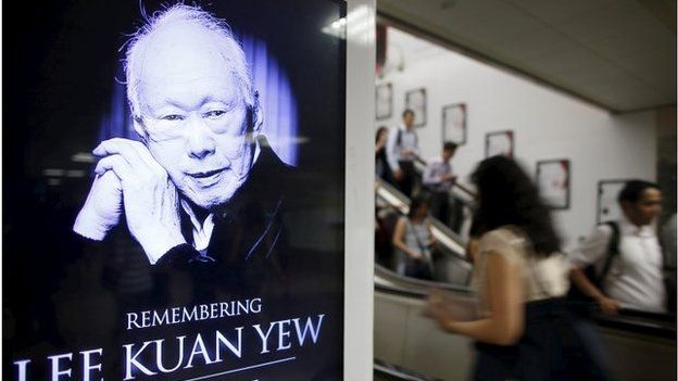 Commuters pass by a signboard displaying a tribute to the late first prime minister Lee Kuan Yew in a train station at the central business district in Singapore 24 March 2015