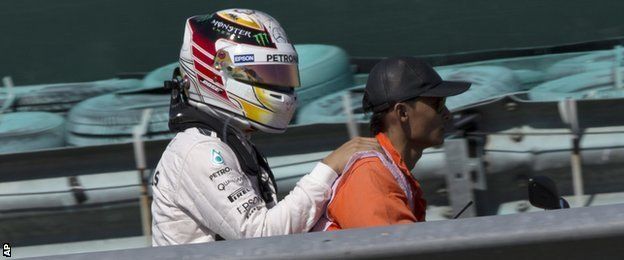 Lewis Hamilton is driven away from his car by a steward