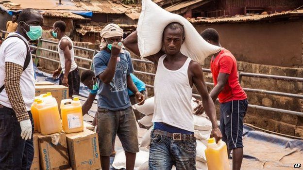 Workers carry food to be distributed to the needy as Sierra Leone enters a three day country wide lockdown on movement of people due to the Ebola virus in the city of Freetown, Sierra Leone, Friday, March. 27, 2015