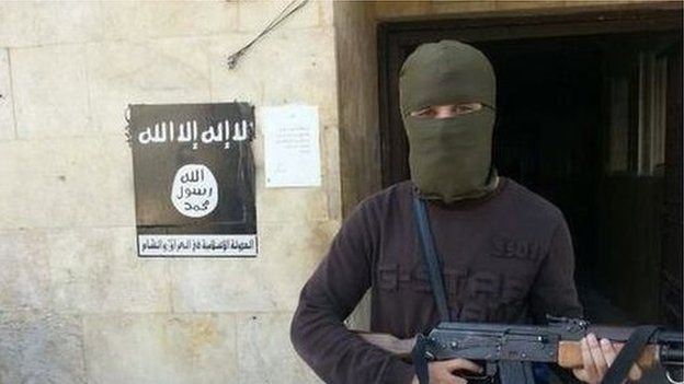 Abu Qa'qa holding a gun, with his face covered