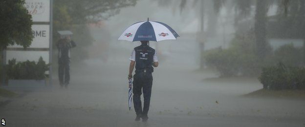 Williams crew member walks in the paddock with an umbrella